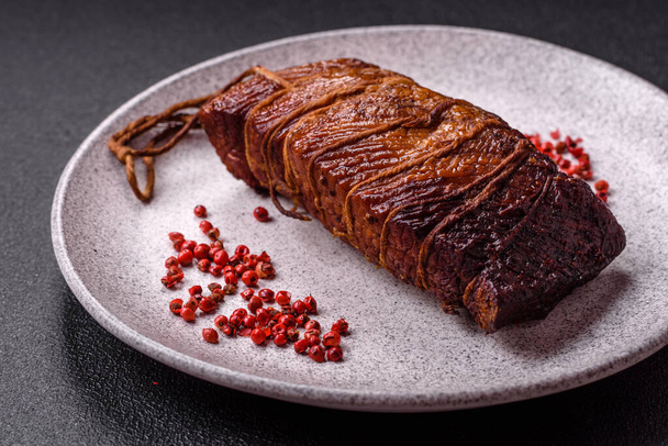 Delicious smoked meat pork or chicken with salt, spices and herbs on a dark concrete background - Photo, Image