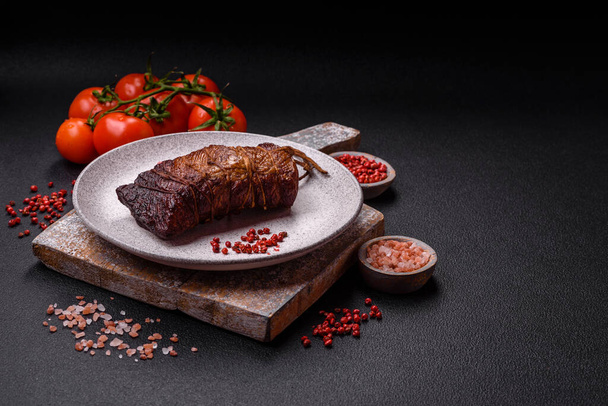 Delicious smoked meat pork or chicken with salt, spices and herbs on a dark concrete background - Photo, Image