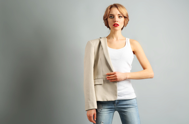 Beautiful young woman in jacket and jeans posing on gray background - Фото, зображення