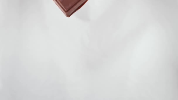 Gran barra de chocolate con leche con fresas liofilizadas y almendras de nueces sobre fondo blanco aislado - Metraje, vídeo