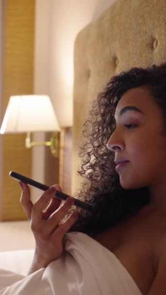 Chica hablando con el teléfono en altavoz en su cama - FHD vídeo vertical - Imágenes, Vídeo
