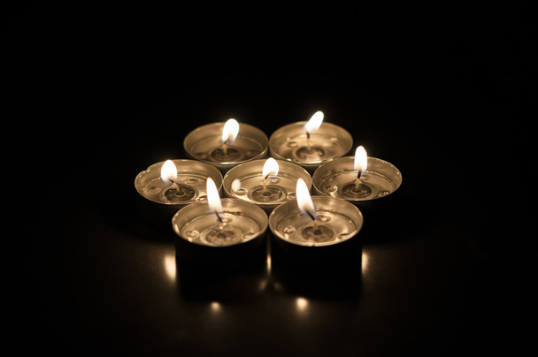 Verschillende kaarsen op een donkere achtergrond door het oppervlak gereflecteerd - Foto, afbeelding