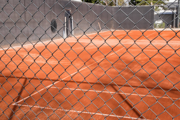 Roter Sand Tennisplatz Oberfläche durch Maschendrahtzaun gesehen - Foto, Bild