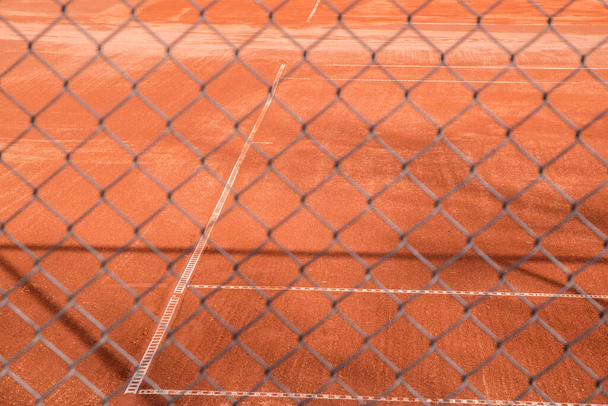 Roter Sand Tennisplatz Oberfläche durch Maschendrahtzaun gesehen - Foto, Bild