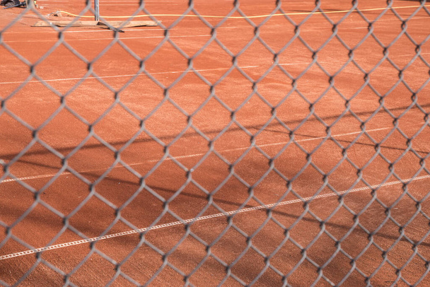 Red clay tennis court surface seen through chain link metal fence - Photo, Image
