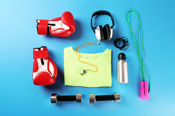 Sports equipment and T-shirt on color table, top view - Foto, Imagen