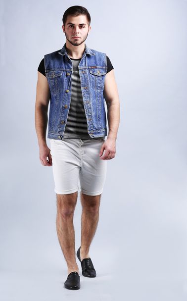 Man in white shorts and jeans vest on gray background - Foto, afbeelding