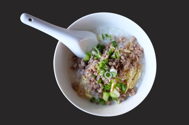 Soft boiled rice with mince pork, Congee in white bowl isolated on black background - Photo, Image