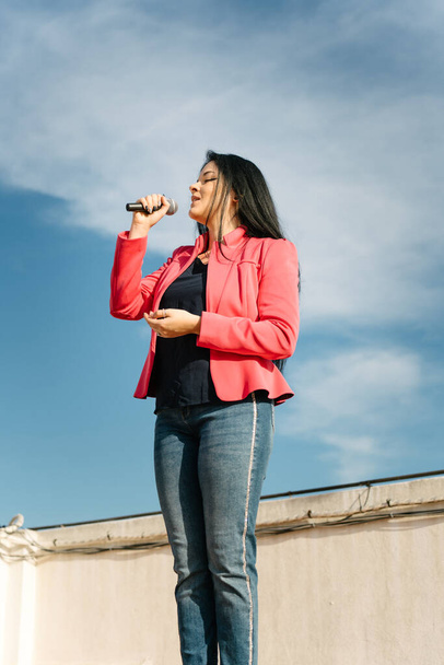 Chanteuse pop chantant avec un microphone sur le toit - Photo, image