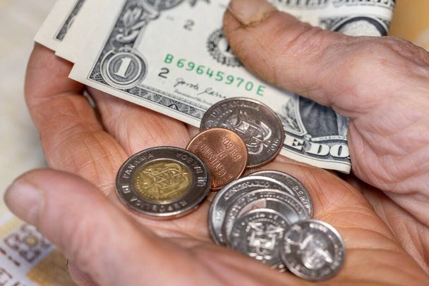 Panama, Hände eines alten Menschen, der eine Handvoll Balboa-Münzen und mehrere Ein-Dollar-Scheine in der Hand hält, Wirtschaftskonzept, Finanzprobleme von Rentnern und Senioren in Panama - Foto, Bild