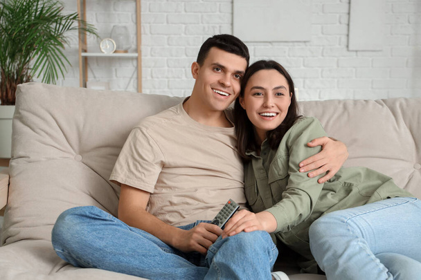 jovem casal assistindo tv no sofá em casa
 - Foto, Imagem