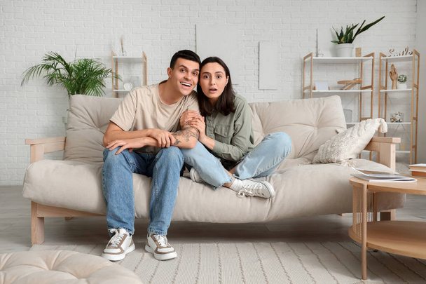 молодая пара смотрит телевизор на диване дома
 - Фото, изображение