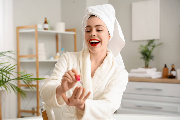 mooi jong gelukkig vrouw doet manicure in badkamer - Foto, afbeelding