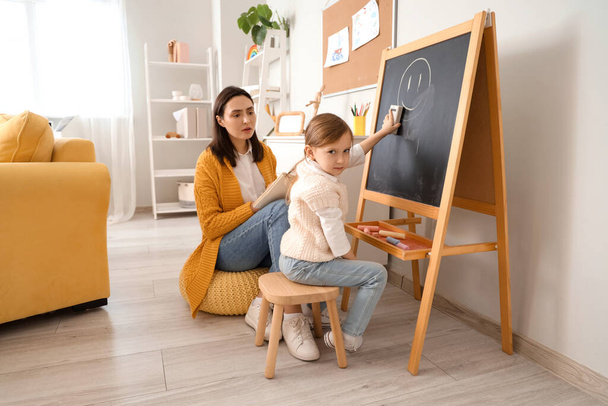 Маленька дівчинка стирає малюнок з дошки в офісі психолога - Фото, зображення