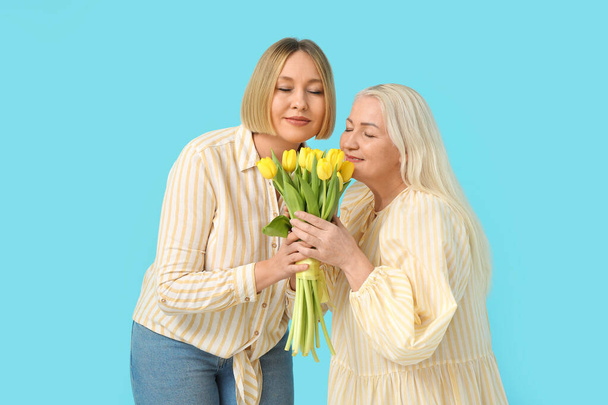 大人の女性は,青い背景にチューリップの花束で母親に挨拶します. 国際女性デーのお祝い - 写真・画像