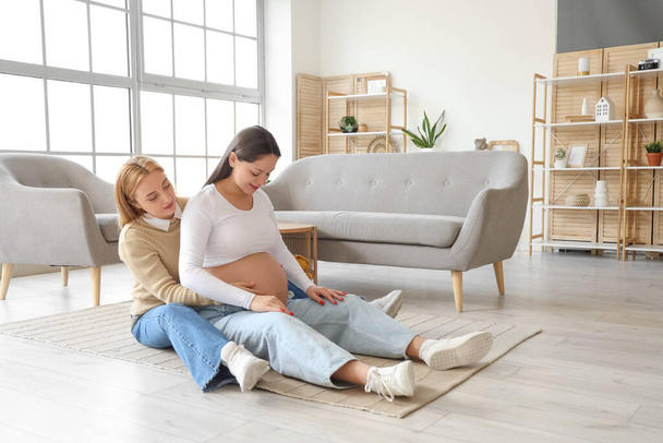 Madura doula con embarazada sentada en el suelo en casa - Foto, imagen