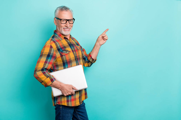 Photo of pretty man pensioner dressed checkered shirt glasses holding device empty space isolated teal color background. - Foto, Imagen