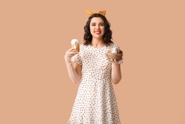Happy pin-up vrouw met paastaart en eieren op kleur achtergrond - Foto, afbeelding