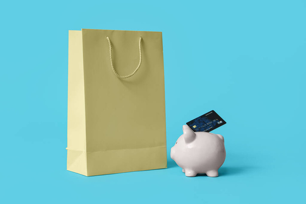 Boodschappentas en spaarpot met kredietkaart op blauwe achtergrond - Foto, afbeelding