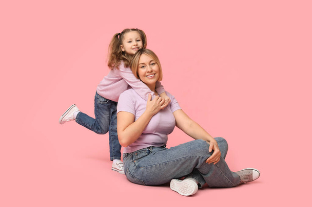 Moeder speelt met haar dochter op roze achtergrond. Moederdag - Foto, afbeelding