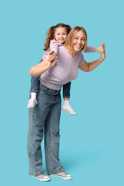 Dziewczynka bawi się z matką na niebieskim tle - Zdjęcie, obraz