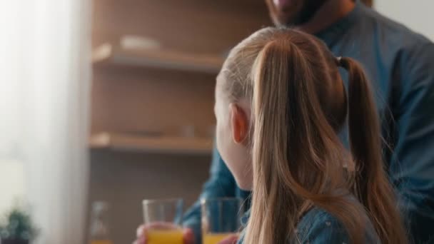 Perhe sairausvakuutus ruoka toimitus terveellinen ravitsemus vitamiinit terveydenhuolto keittiö onnellinen mies isä tuo kaksi lasillista oranssi tuoremehua tytär lapsi tyttö laptop e-oppimisen juominen yhdessä - Materiaali, video