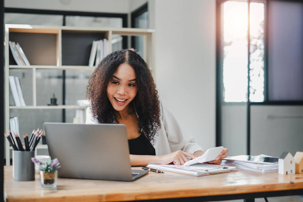 Opgewonden zakenvrouw beleeft een moment van succes tijdens het werken op haar laptop in een goed uitgeruste, zonovergoten kantoor. - Foto, afbeelding