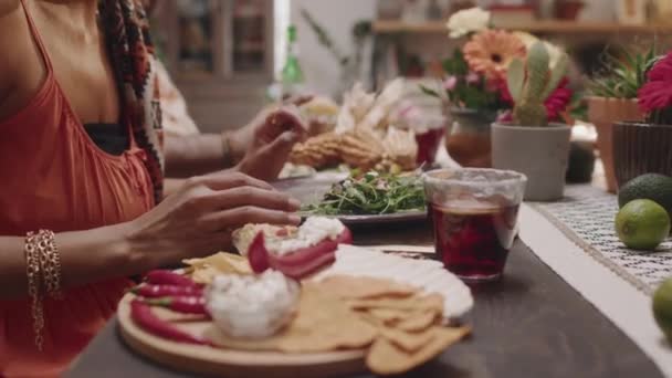 Середня крупним планом сота рук і середини секції мексиканської жінки, сидячи за партійним столом з друзями і розмовляючи, насолоджуючись традиційною кухнею і напоями, у відпустці або сім'ї - Кадри, відео