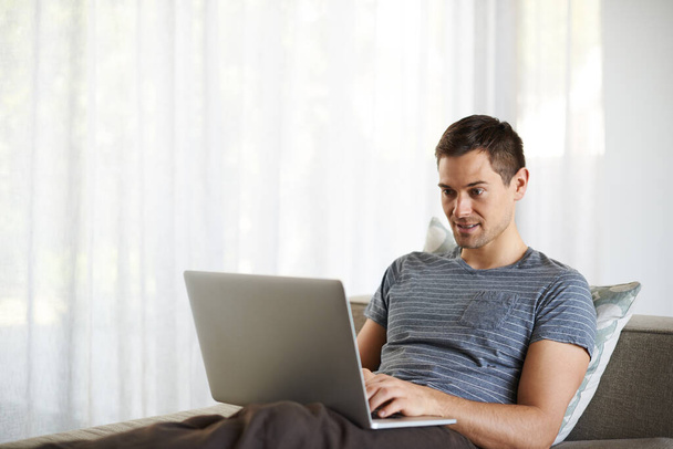 Relax, remote work and man on sofa with laptop for working from home, freelance job and career. Business, startup and person on computer for typing email, planning or internet research on website. - Photo, Image