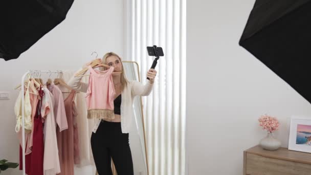 Молодая социальная медиа контент создатель женщина сделать модное видео с помощью селфи палку. Блогер улыбается в камеру, заставляя убедительную онлайн-одежду продавать блог аудитории или последователю. Блайт - Кадры, видео