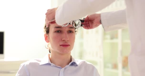 Офтальмолог розміщує окуляри на обличчі пацієнта, щоб перевірити зір. Доктор ретельно оцінює зір та виявляє потенційні проблеми повільного руху - Кадри, відео