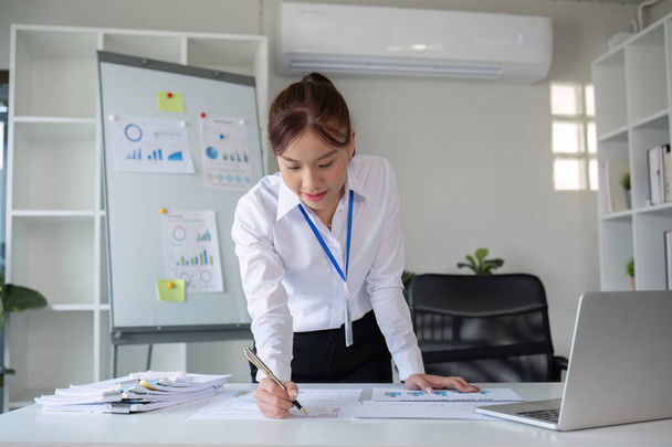 Une femme d'affaires avec détermination prend note, rédige un plan de travail et trace le calendrier financier de l'entreprise dans son bureau.. - Photo, image