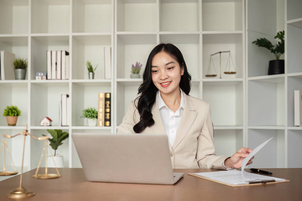 A female Asian lawyer reviews business and real estate laws. Legal consultants provide legal advice and guidance online via laptops in lawyers offices.. - Photo, Image