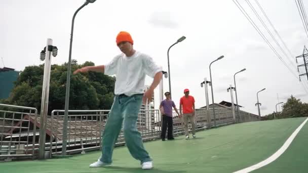 Professzionális hipszter séta közben fagyálló pózban a hídnál. Break táncos végre hip hop lépés körül csoport hipster éljenzés vagy bátorító barát. Kültéri sport 2024. Élénk.. - Felvétel, videó