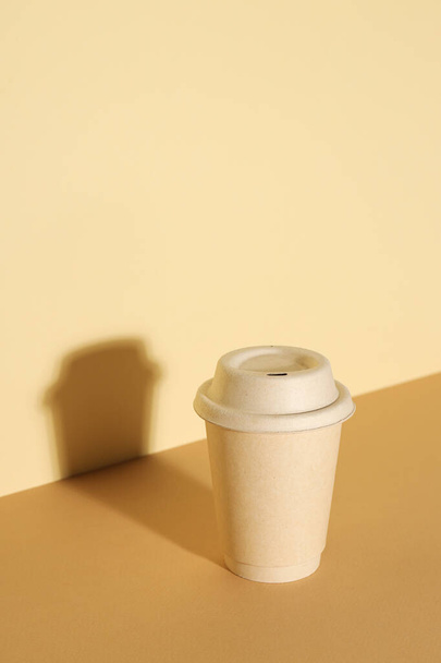 Una taza de papel con tapa sobre un fondo claro - Foto, imagen