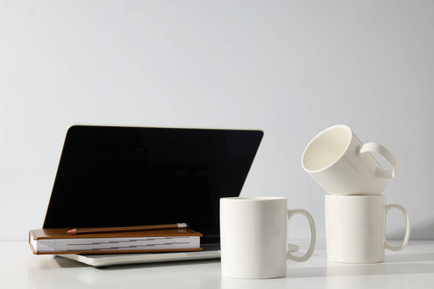 Білі чашки на столі з ноутбуком - Фото, зображення