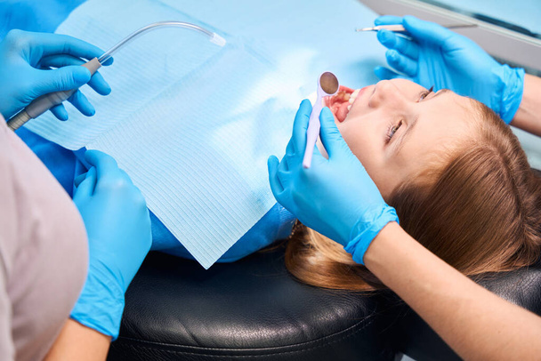 Adolescente en la silla de dentistas, el personal médico utiliza instrumentos dentales especiales en el trabajo - Foto, imagen