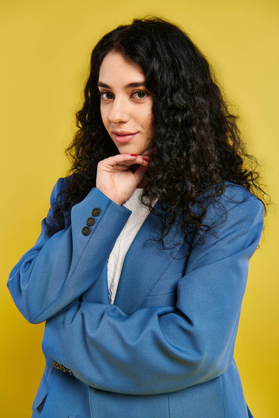 Brunette femme en costume bleu met en valeur l'élégance et la confiance, posant dans un studio avec un fond jaune. - Photo, image
