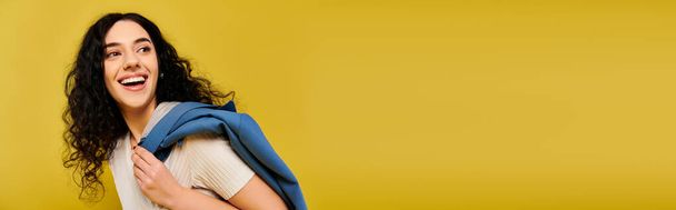 Стильная молодая женщина с кудрявыми волосами, пойманная на ярко-желтом фоне. - Фото, изображение