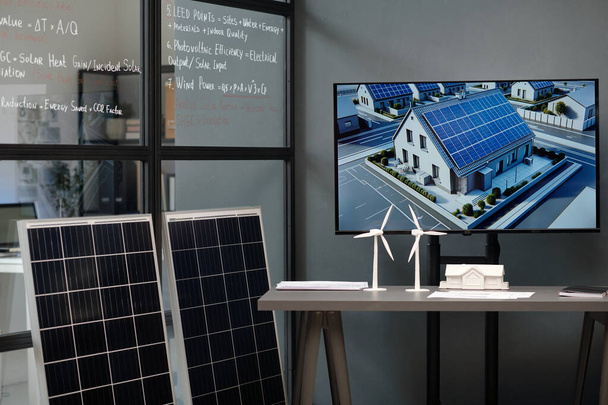 Etkileşimli panolarda güneş panelleri ve masasında yel değirmeni modelleri olan modern mimarın çalışma yeri - Fotoğraf, Görsel