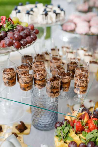 Een houten tafel toont een verscheidenheid aan desserts en cupcakes in kleurrijke wikkels en bevriezingen, waardoor een verleidelijke en heerlijke spreiding. - Foto, afbeelding