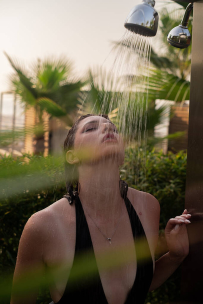 Дівчина, що приймає душ біля моря: епітом пляжної релаксації. Ідеально підходить для курортних готелів, пляжних продуктів, догляду за сонцем, екотуризму та натуральної косметики - Фото, зображення