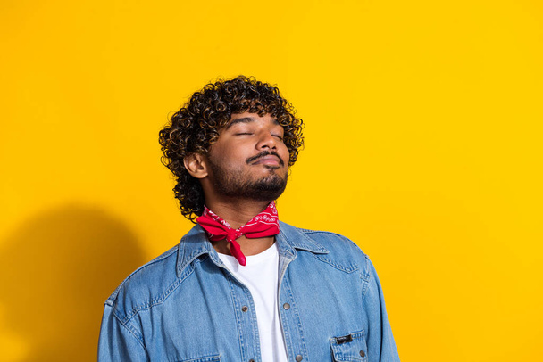 Photo portrait of nice young male closed eyes smell sweet aroma wear trendy denim outfit red scarf isolated on yellow color background. - Fotó, kép