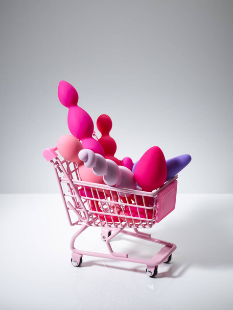 anal plugs and dildo sex toys in shopping basket isolated on white background - Fotó, kép