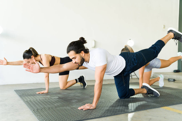 Diverses personnes s'engagent dans une routine de remise en forme équilibrée dans une salle de gym bien éclairée, pratiquant la coordination et la force - Photo, image
