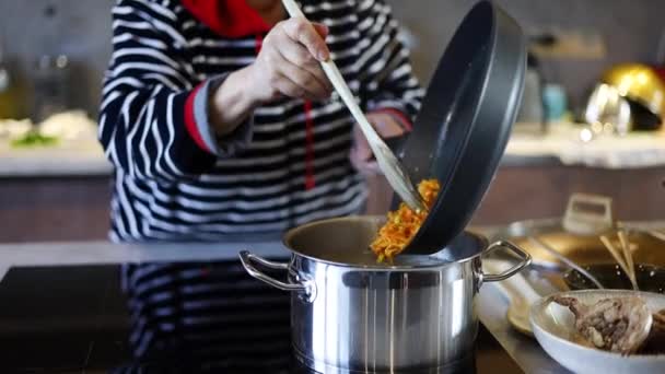 Seniorin kocht Suppe in Küche. Großaufnahme einer Hausfrau, die zu Hause in Zeitlupe mit dem Löffel Suppe rührt. Köchin steht am Herd in häuslicher Küche - Filmmaterial, Video
