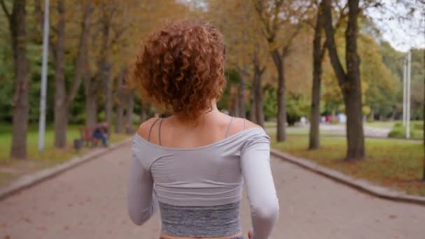 秋の公園でスポーツ屋外自然少女は,認識できない女性のアスリートカーディオ運動の背後からバックビューを実行 朝のトレーニングウェルネスマラソンのトレーニングジョギングで実行フィットネスランナー - 映像、動画