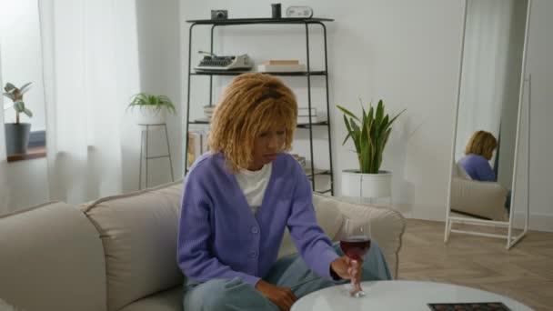 Kalm ontspannen verdrietig Afrikaans Amerikaans meisje alleen ontspannen rustige vrouw slechte gewoonte vrouw thuis woonkamer appartement met glas rode wijn genieten van alcohol verslaafde drinken drinken drinken denken - Video