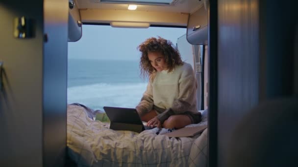 Χαλαρή επιχειρηματίας που κοιτάζει οθόνη laptop κάθεται κρεβάτι ρυμουλκούμενο στο λυκόφως. Σγουρή μεσήλικη γυναίκα που δουλεύει στον υπολογιστή στο τροχόσπιτο μόνη της. Σοβαρή κυρία freelancer ανάγνωση smartphone στο τροχόσπιτο. - Πλάνα, βίντεο