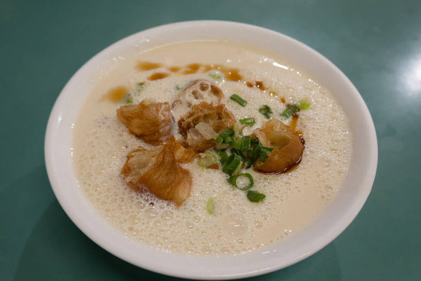 Чаша соевого супа с соевым молоком с палочками для жареного теста и луковицами. - Фото, изображение